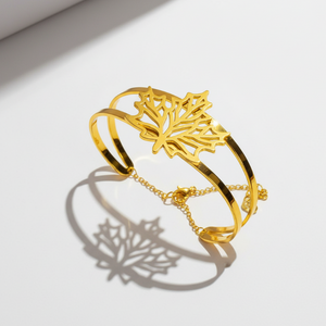 Gold-plated autumn leaf bracelet with double-frame open cuff design and intricate cut-out leaf centerpiece on white background